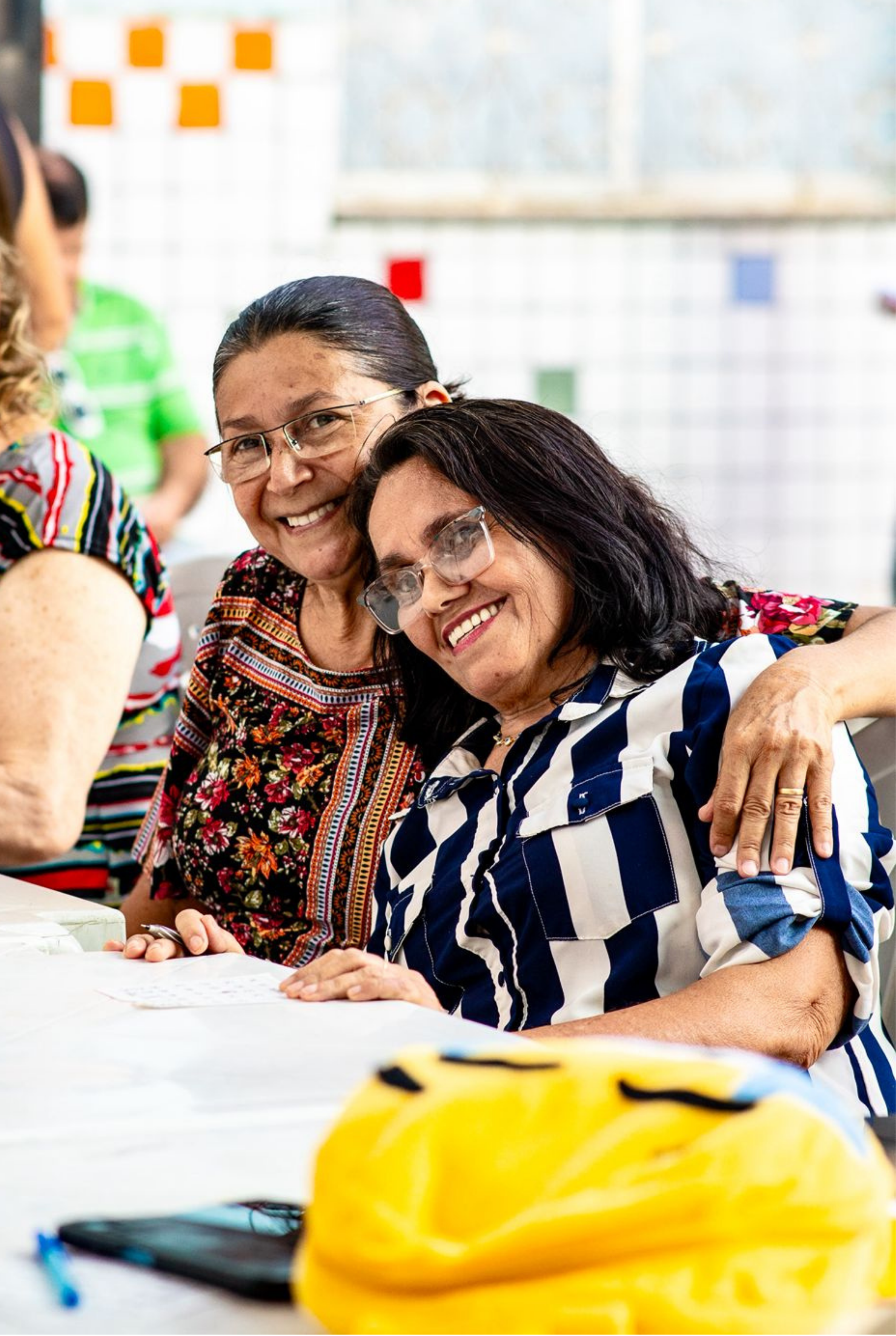 Duas participantes do Tempo de Viver sorrindo e abraçadas durante um encontro no IEIS