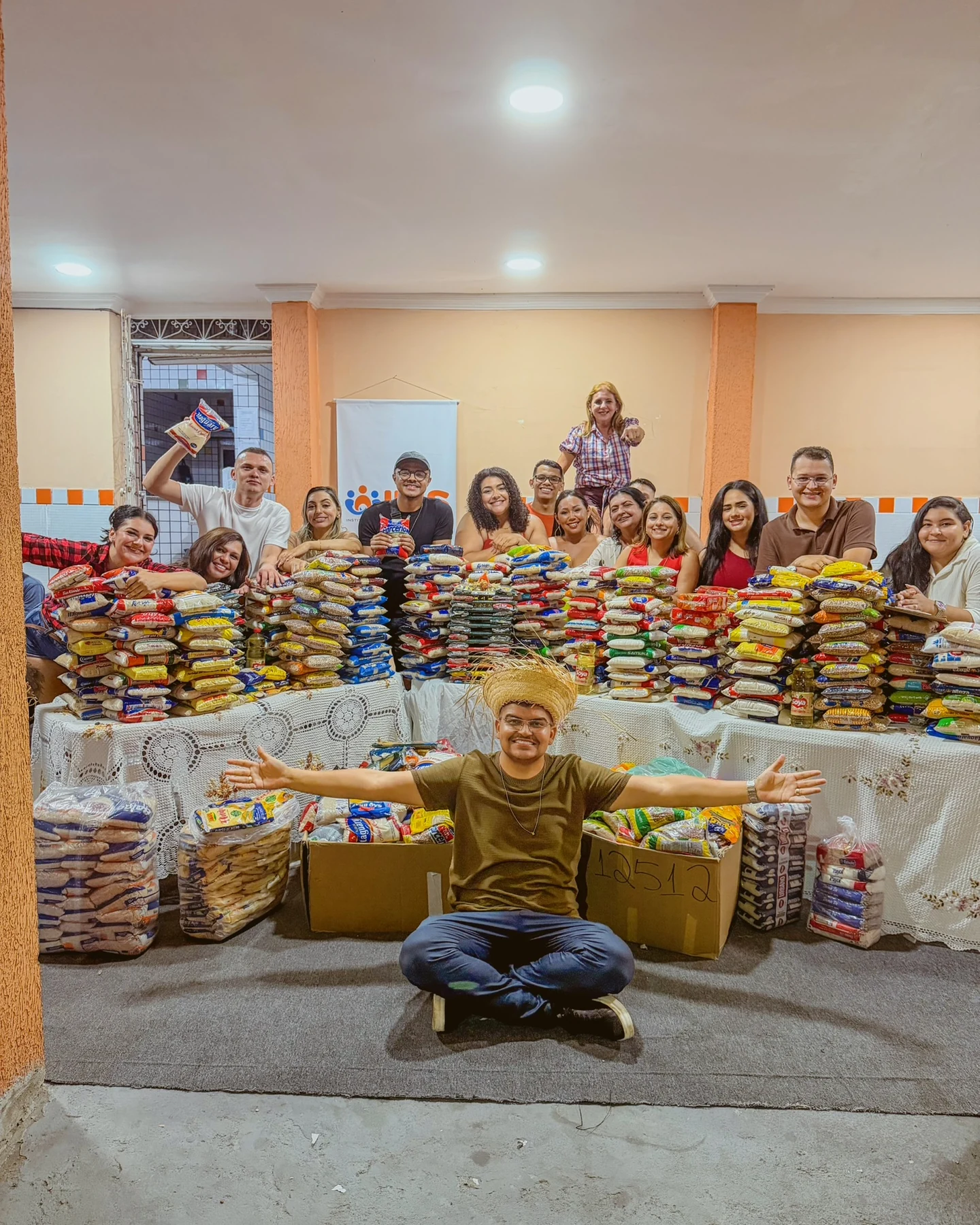 Equipe e comunidade reunidas com os alimentos arrecadados no arraiá, unindo celebração cultural e solidariedade · 2026