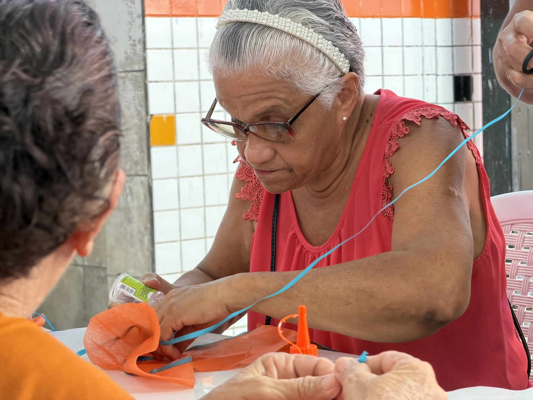 Participante desenvolve trabalho manual com tecido e tesoura, valorizando a criatividade e o aprendizado compartilhado nas oficinas do Tempo de Viver · 2026