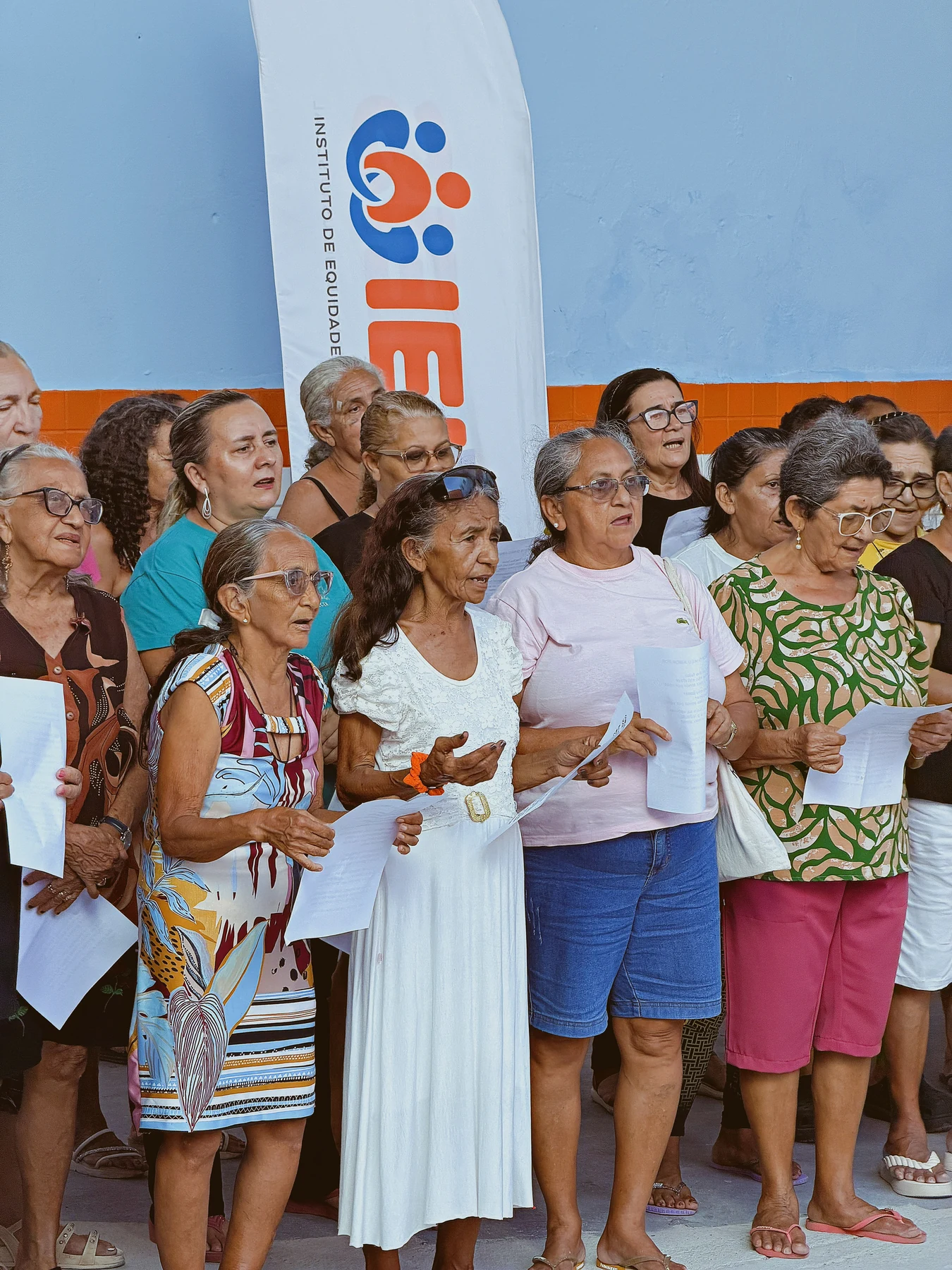 Integrantes acompanham as letras das canções durante a prática do canto coletivo, compartilhando vozes e experiências · 2026