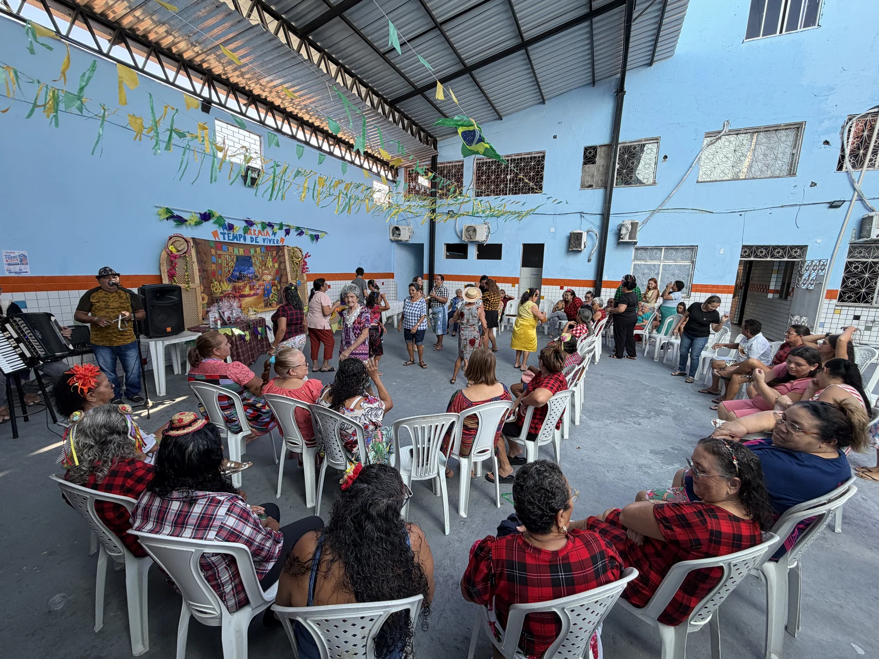 Roda de dança durante o arraiá do grupo, com participação das pessoas idosas e integração dos presentes · 2026